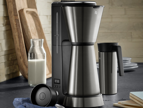 WMF K&Uuml;CHENminis Kaffeemaschine Thermo to go cromargan matt auf einer Arbeitsplatte mit einer Flasche Milch